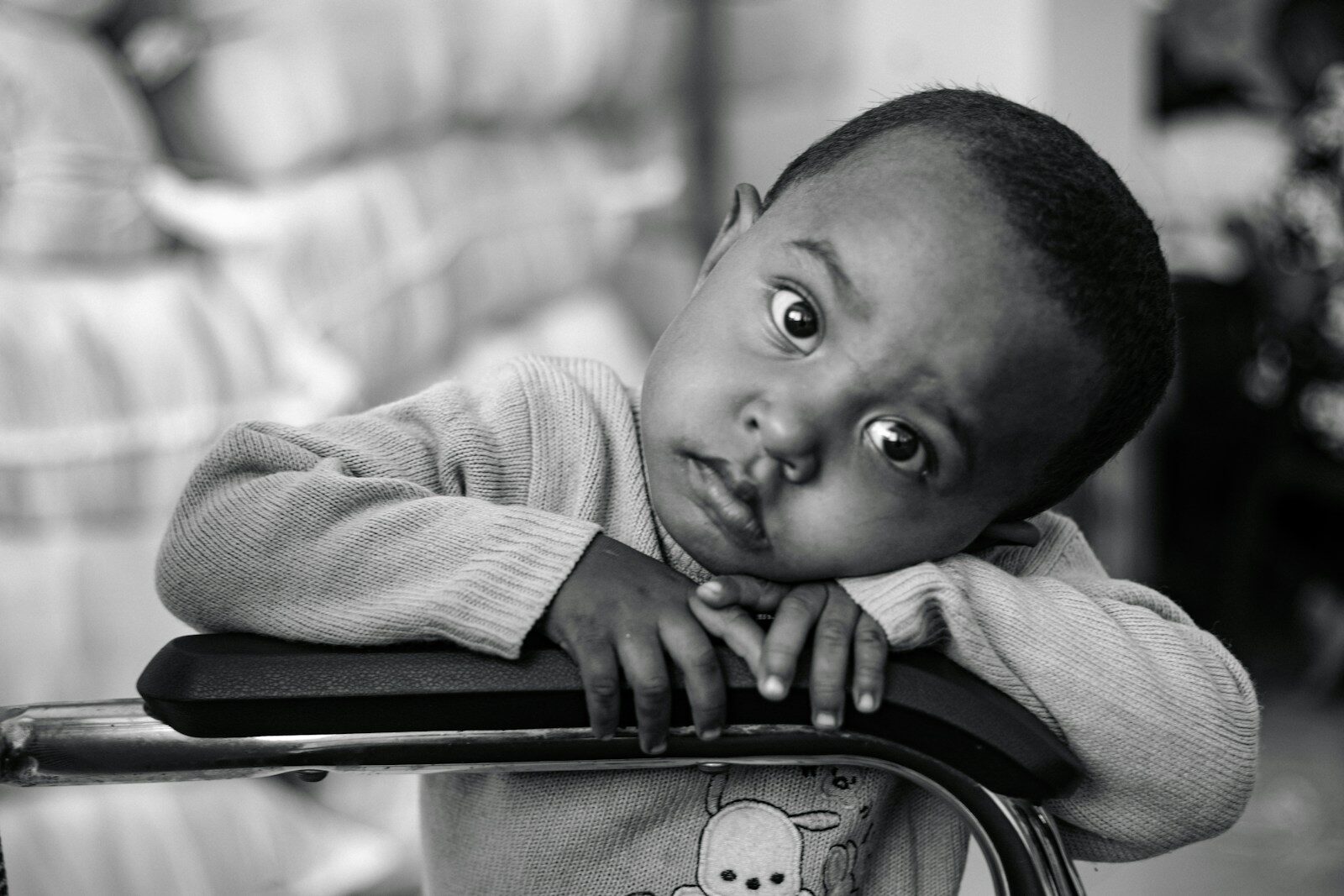 a young boy leaning on a chair with his hand on his chin